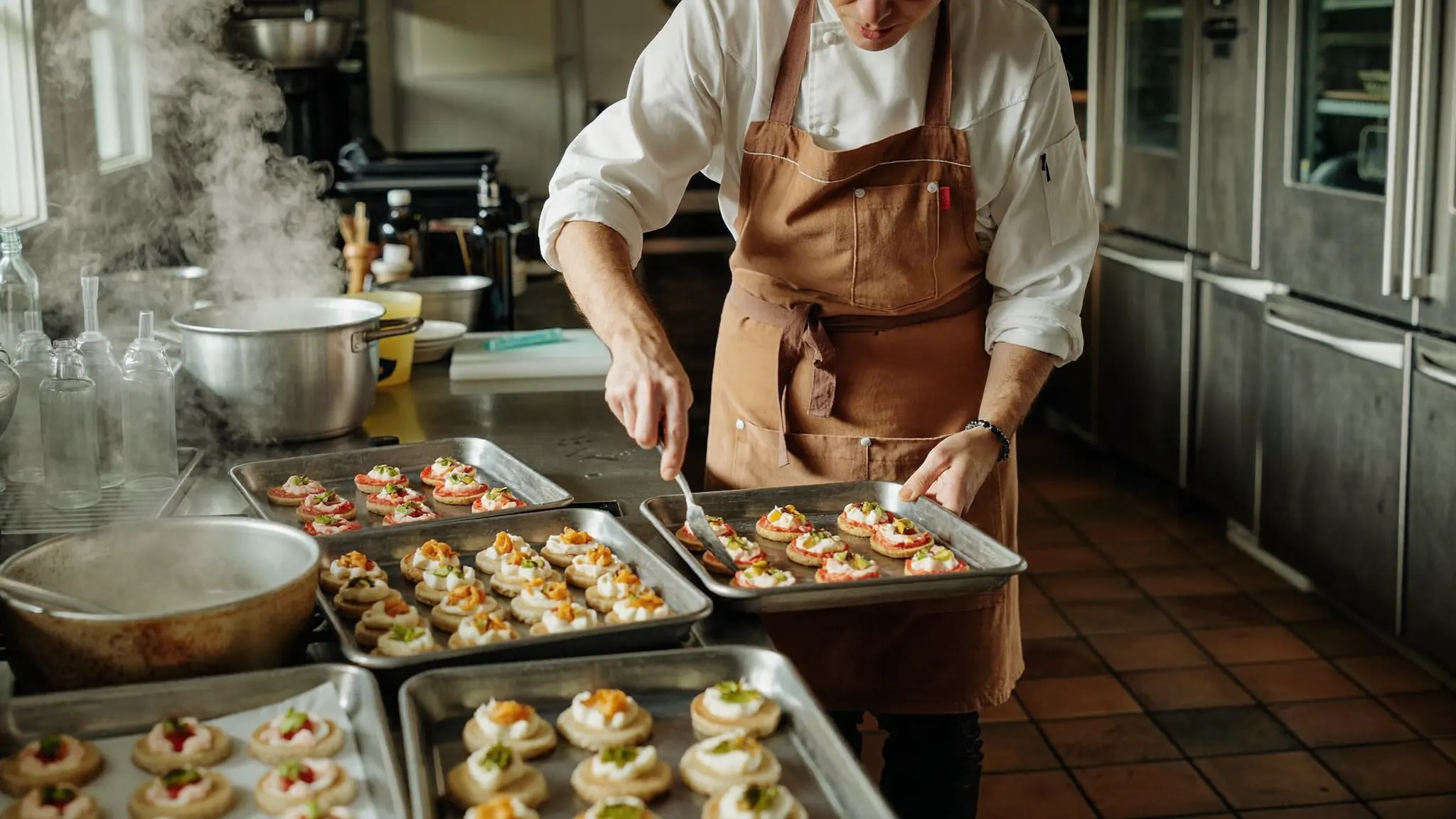 Caterer in a chef's apron plating appetizers in a catering kitchen