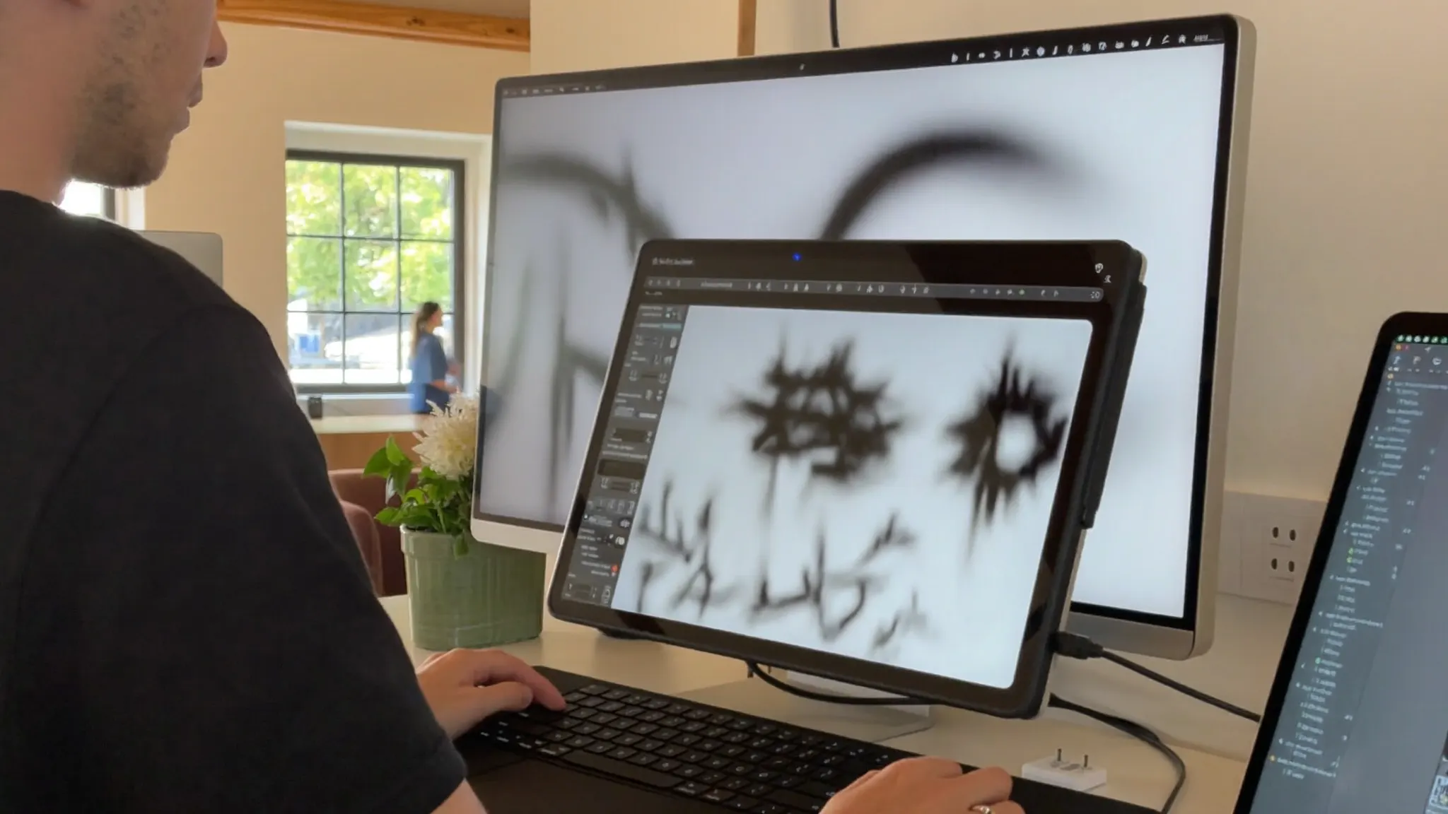 Graphic designer working at a desktop computer with a drawing tablet