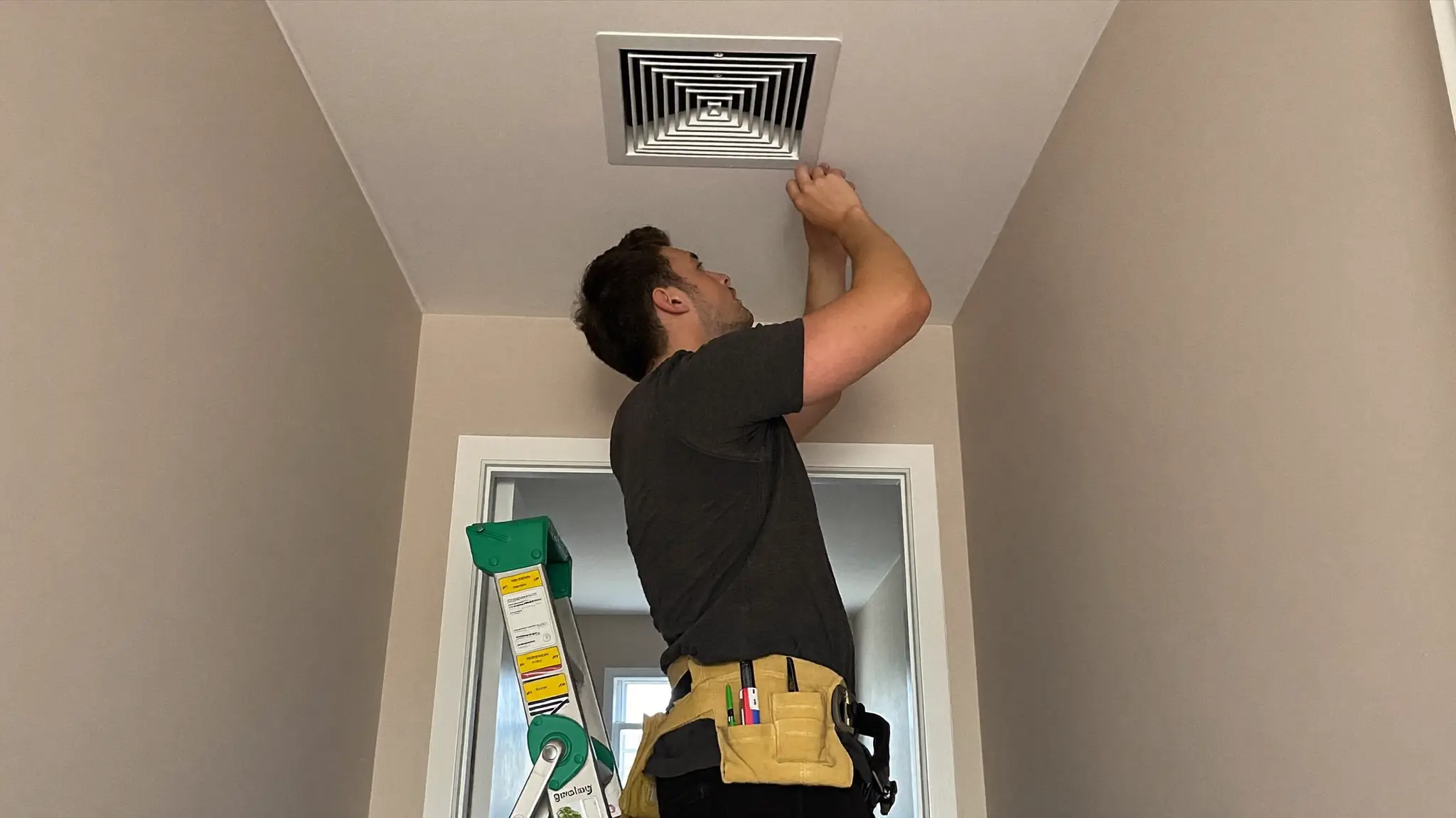 HVAC technician's hands adjusting a valve on outdoor copper refrigerant lines beside a house