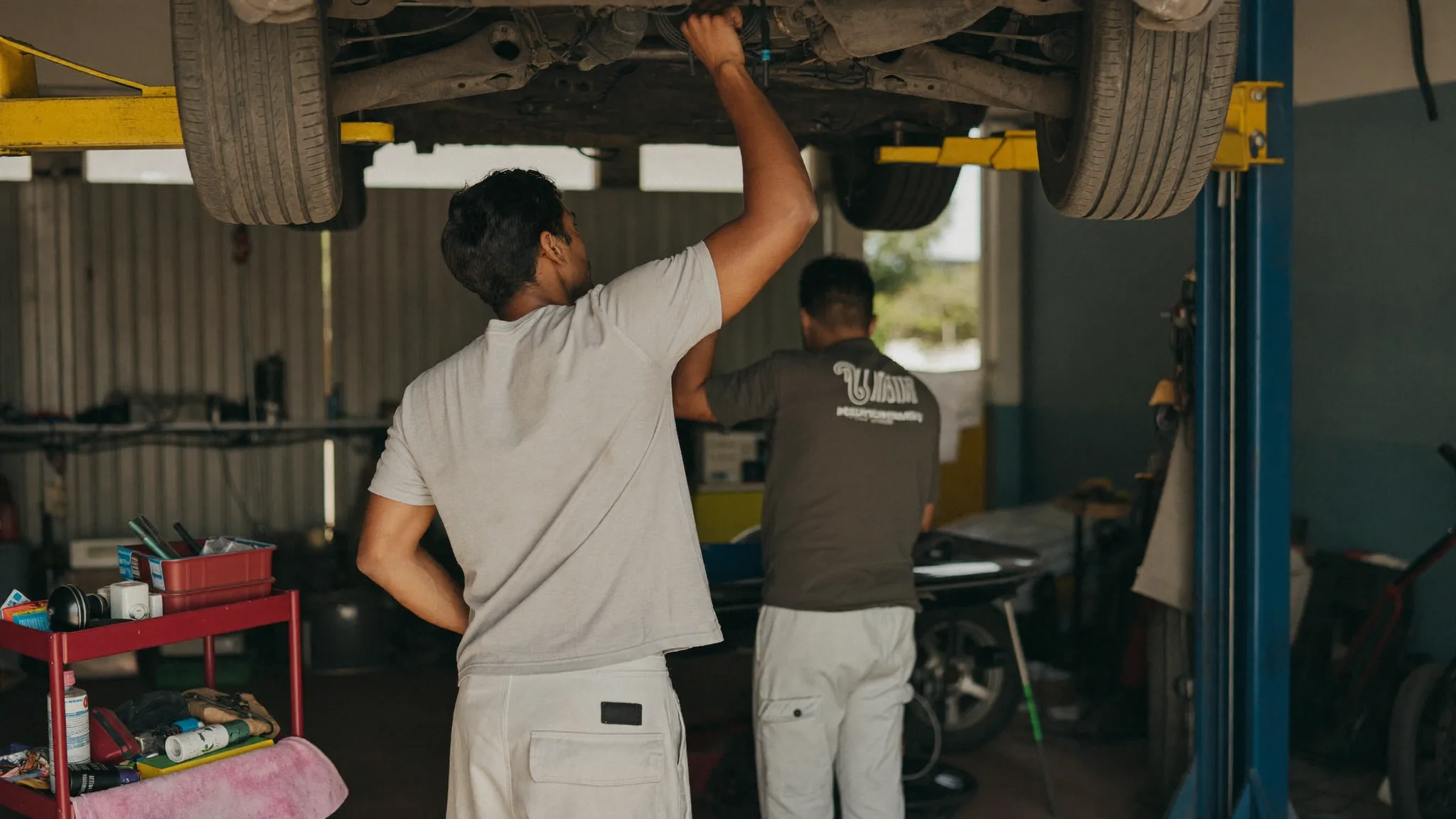 Mechanic working underneath a car on a lift in a repair shop