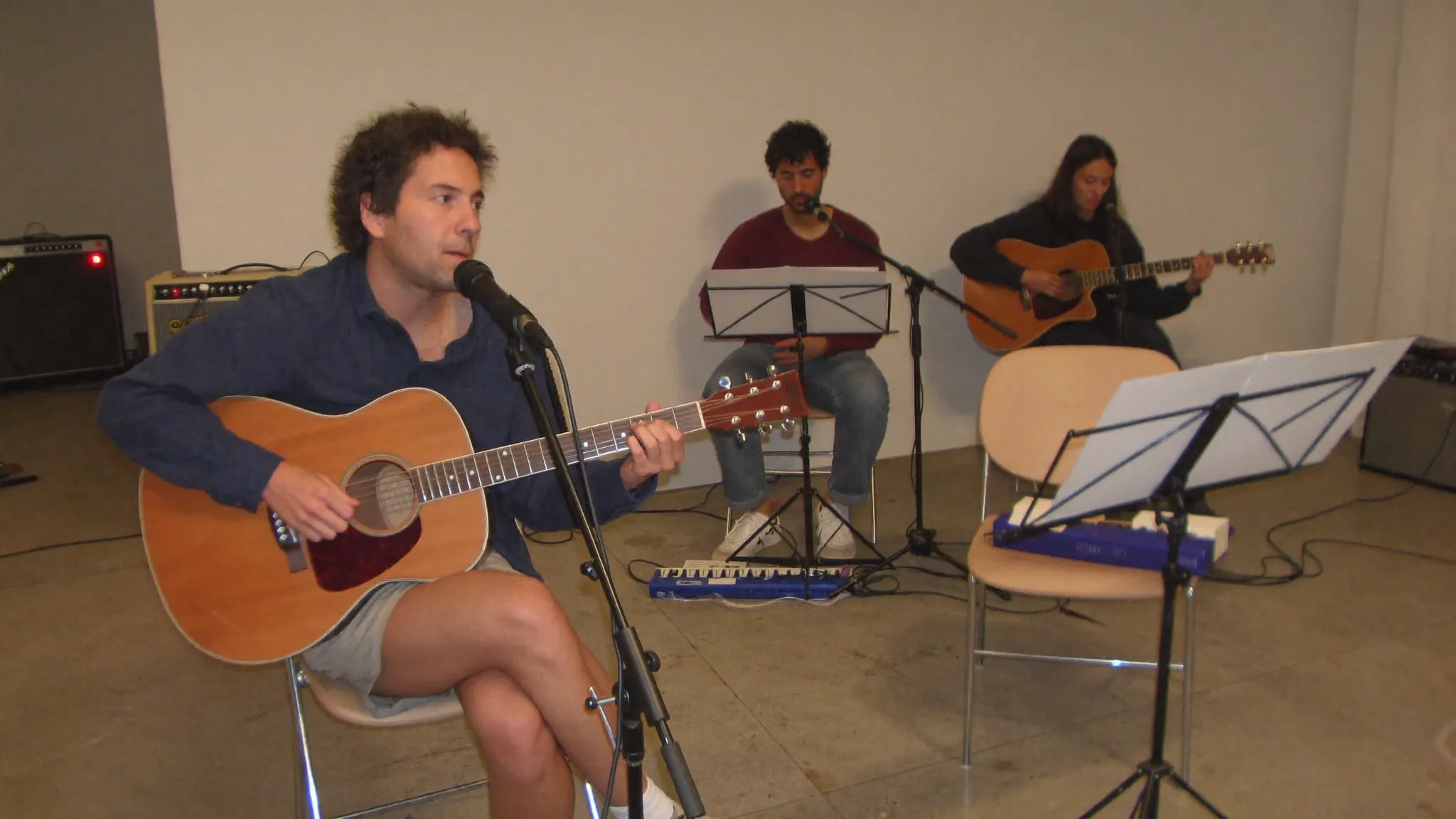 Musician playing an acoustic guitar during a band rehearsal