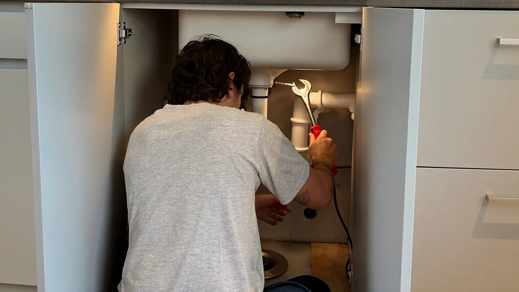 Plumber working under a kitchen sink in a client's home