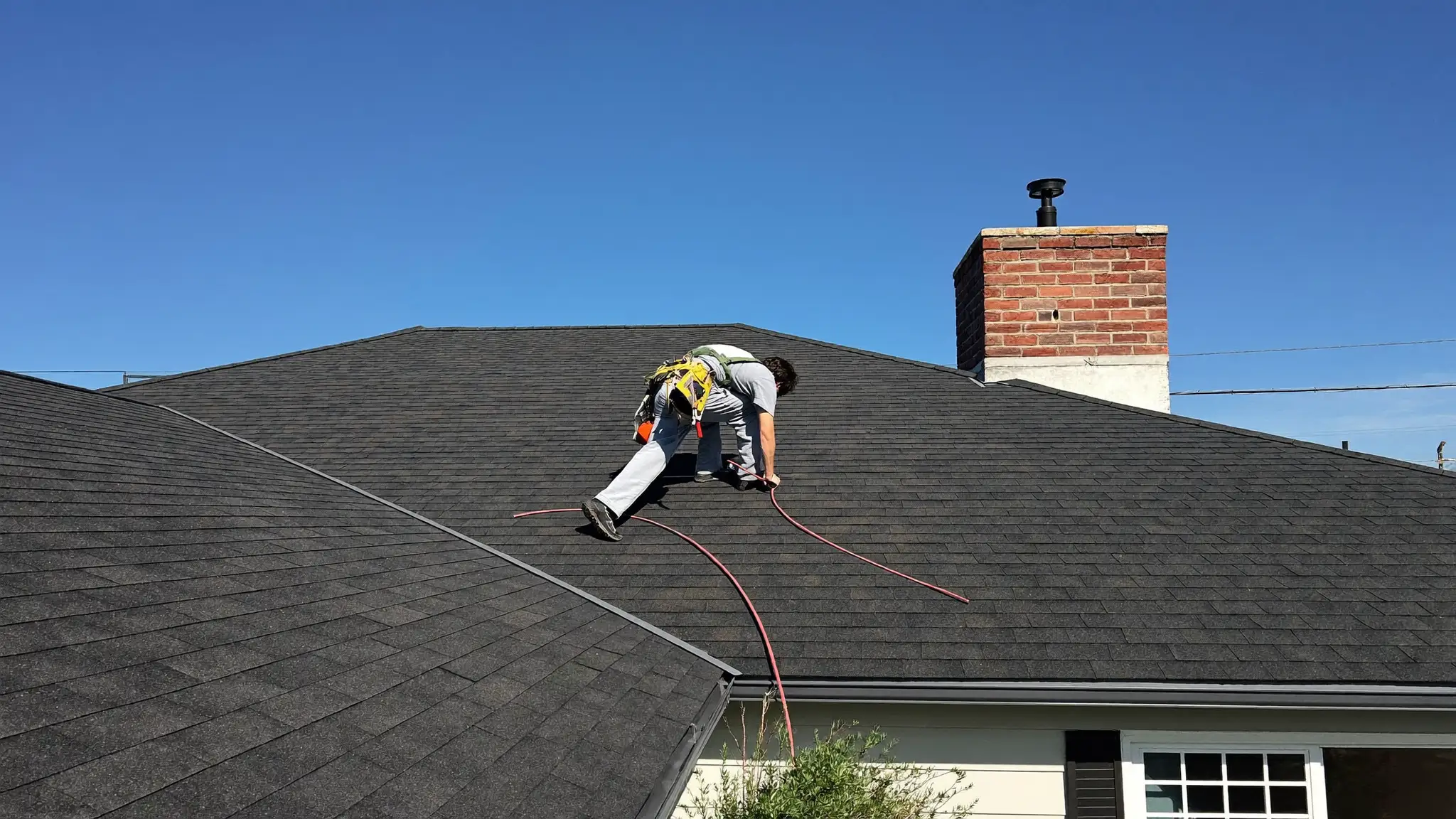 Roofer installing asphalt shingles on a house rooftop