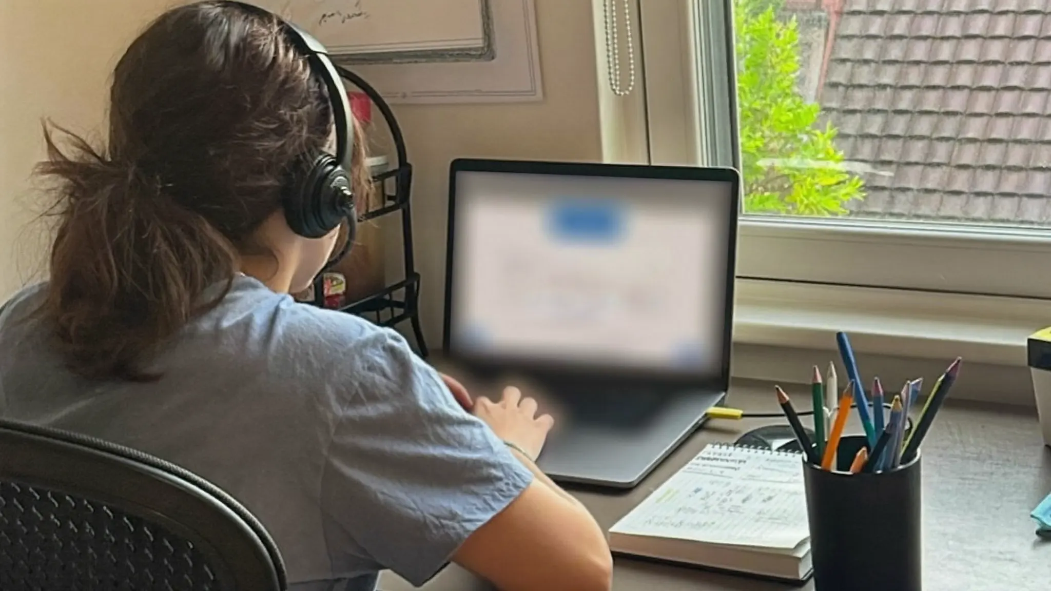 Virtual assistant wearing a headset working at a laptop in a home office