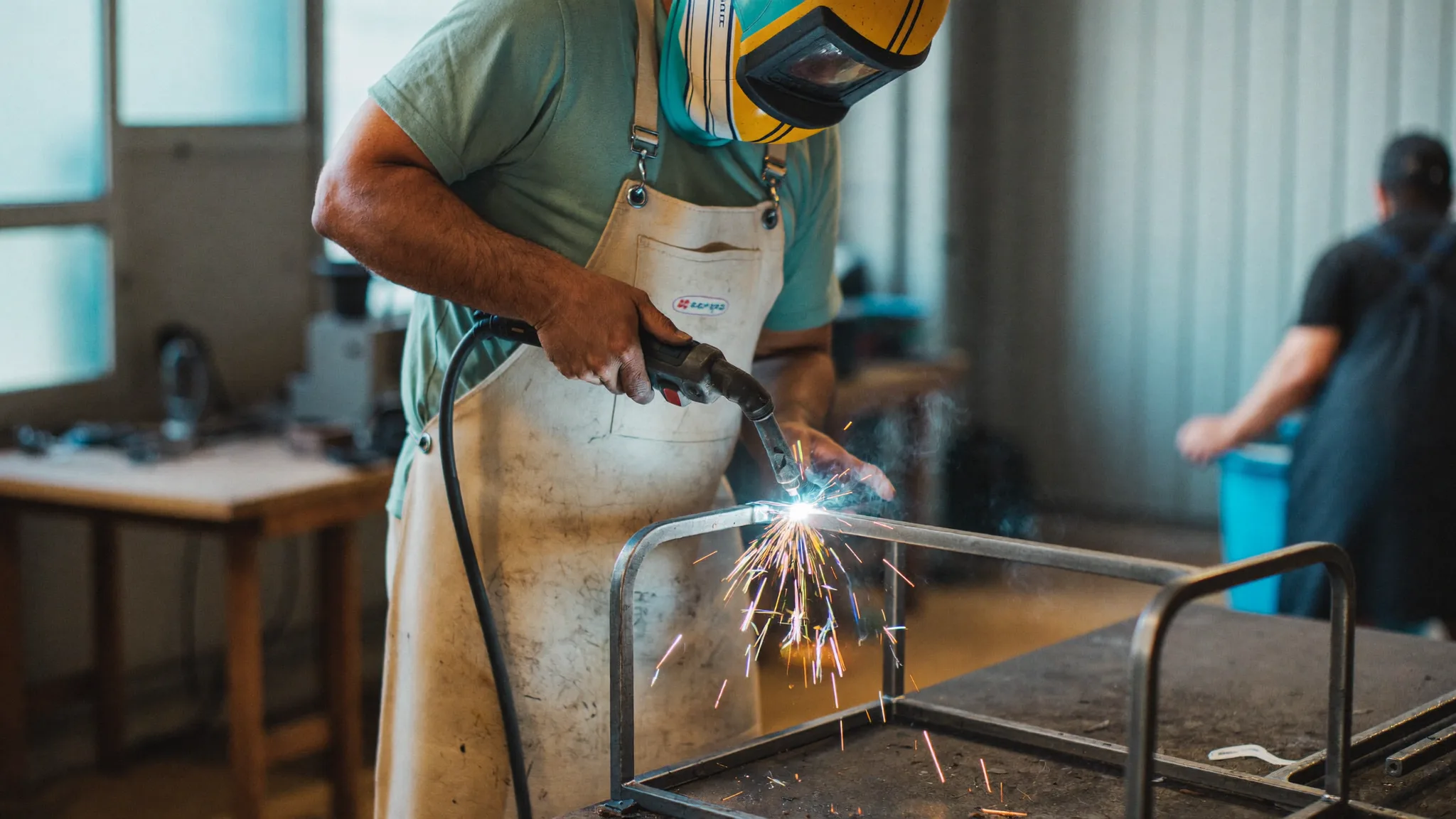 Welder in protective gear working on a metal fabrication project