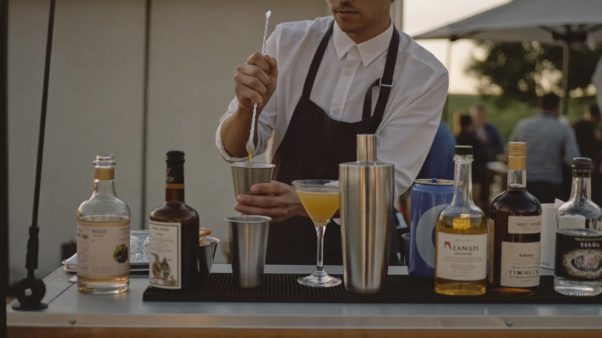 Mobile bartender mixing drinks behind a portable bar at a private event