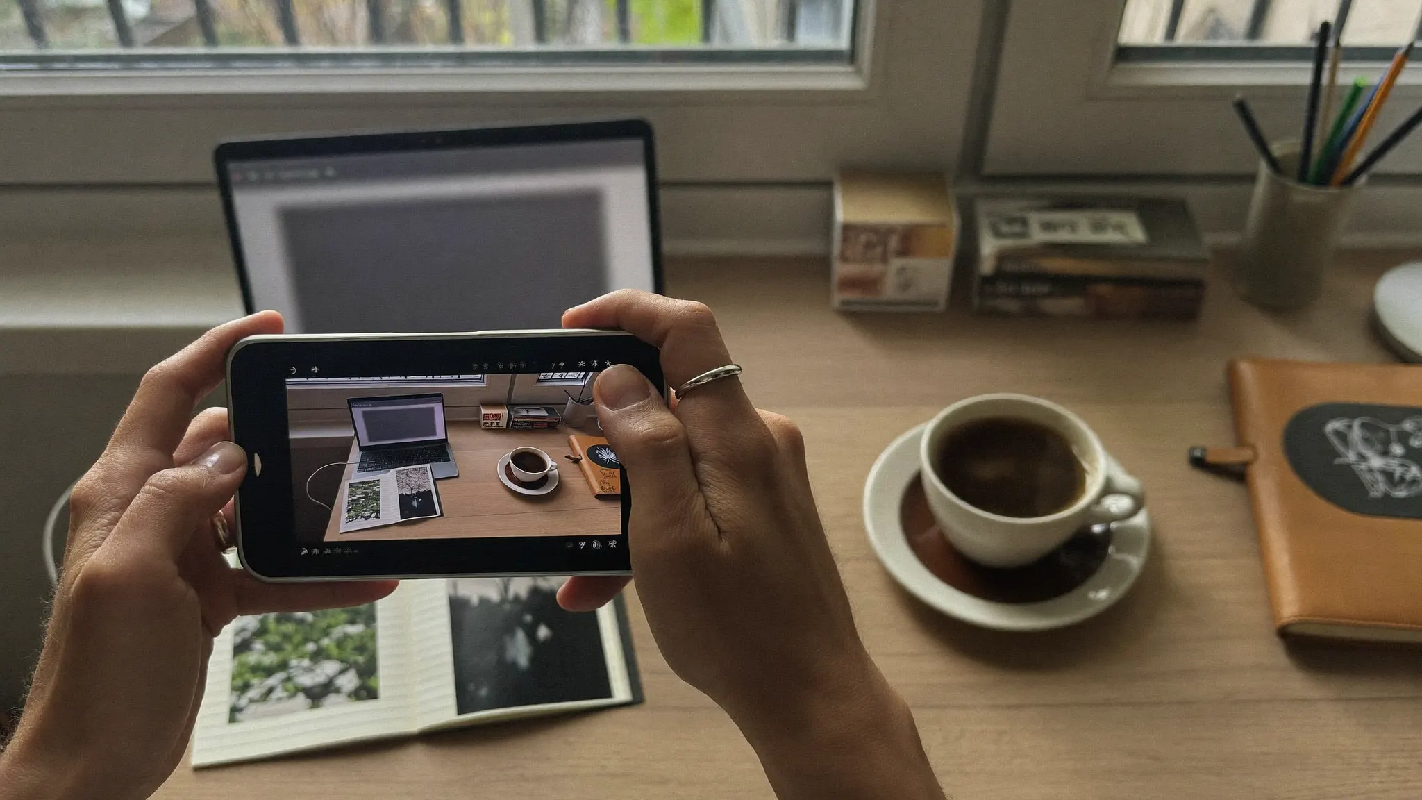 Blogger photographing a styled flat-lay of a coffee cup and notebook on a desk