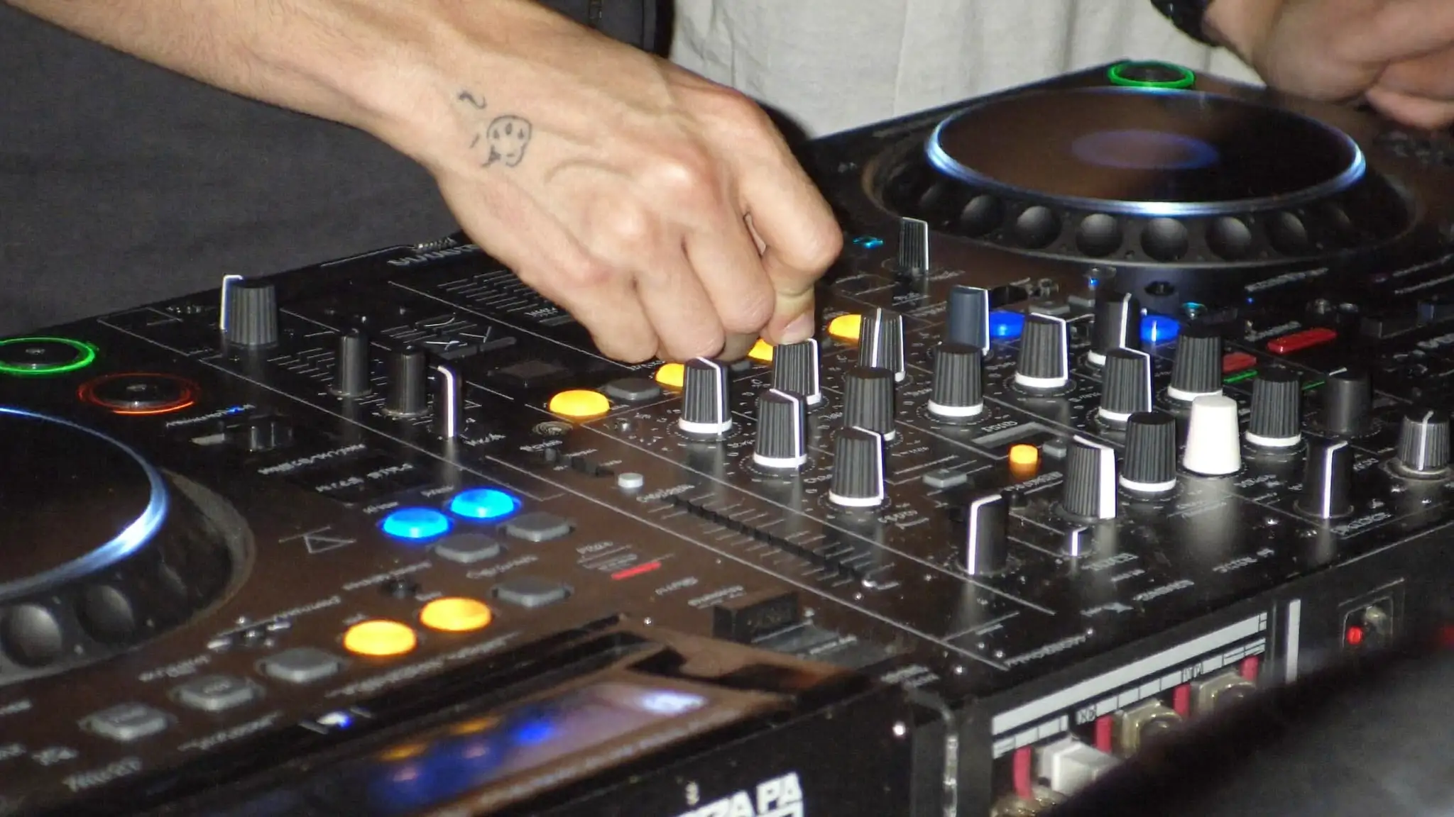 Close-up of a DJ's hands adjusting knobs on a mixer at an event