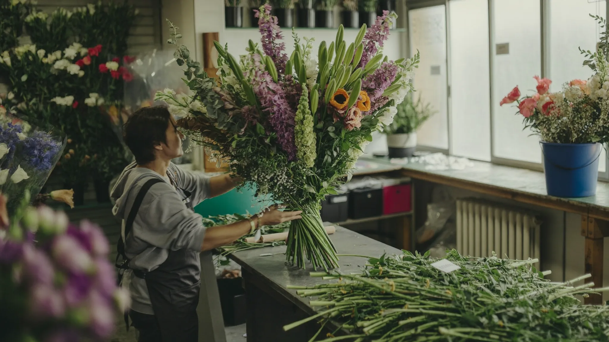 Florist arranging a bouquet of flowers at a work table in a flower shop