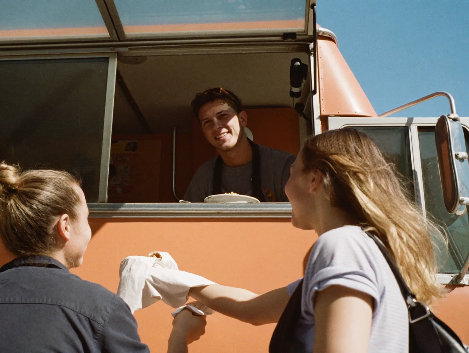 Food truck owner serving customers at a service window