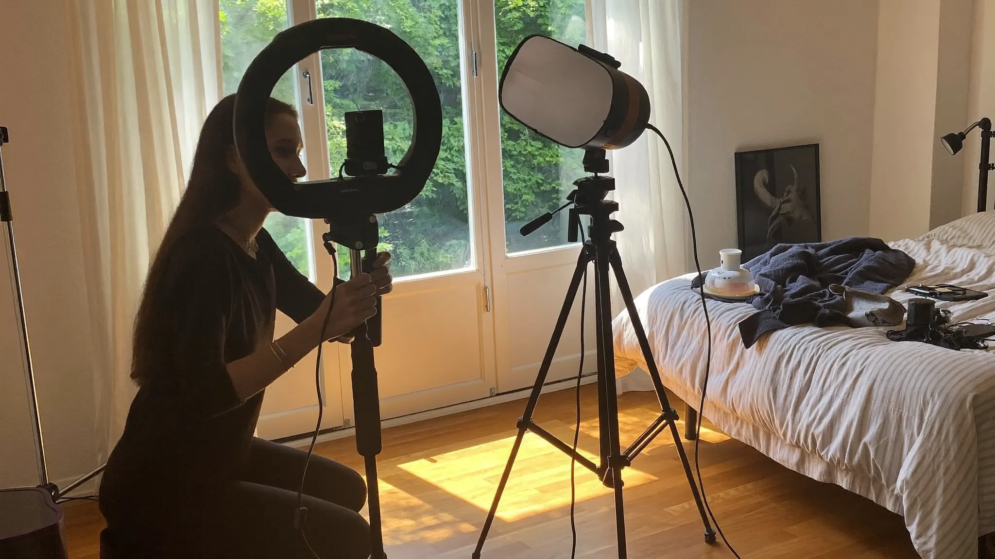 Content creator adjusting a ring light and camera setup in a bedroom studio before recording