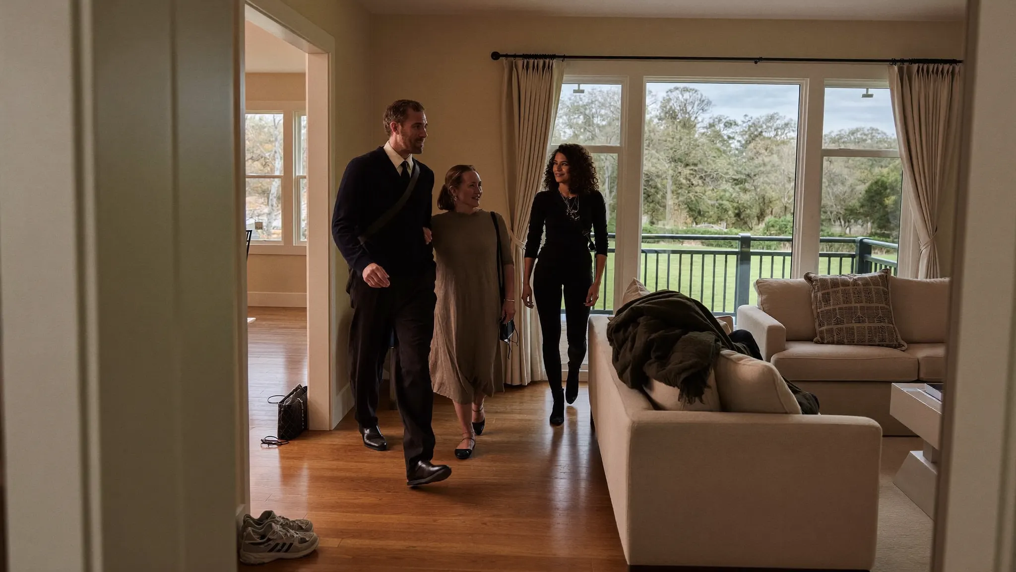 Real estate agent walking clients through the living room of a house for sale