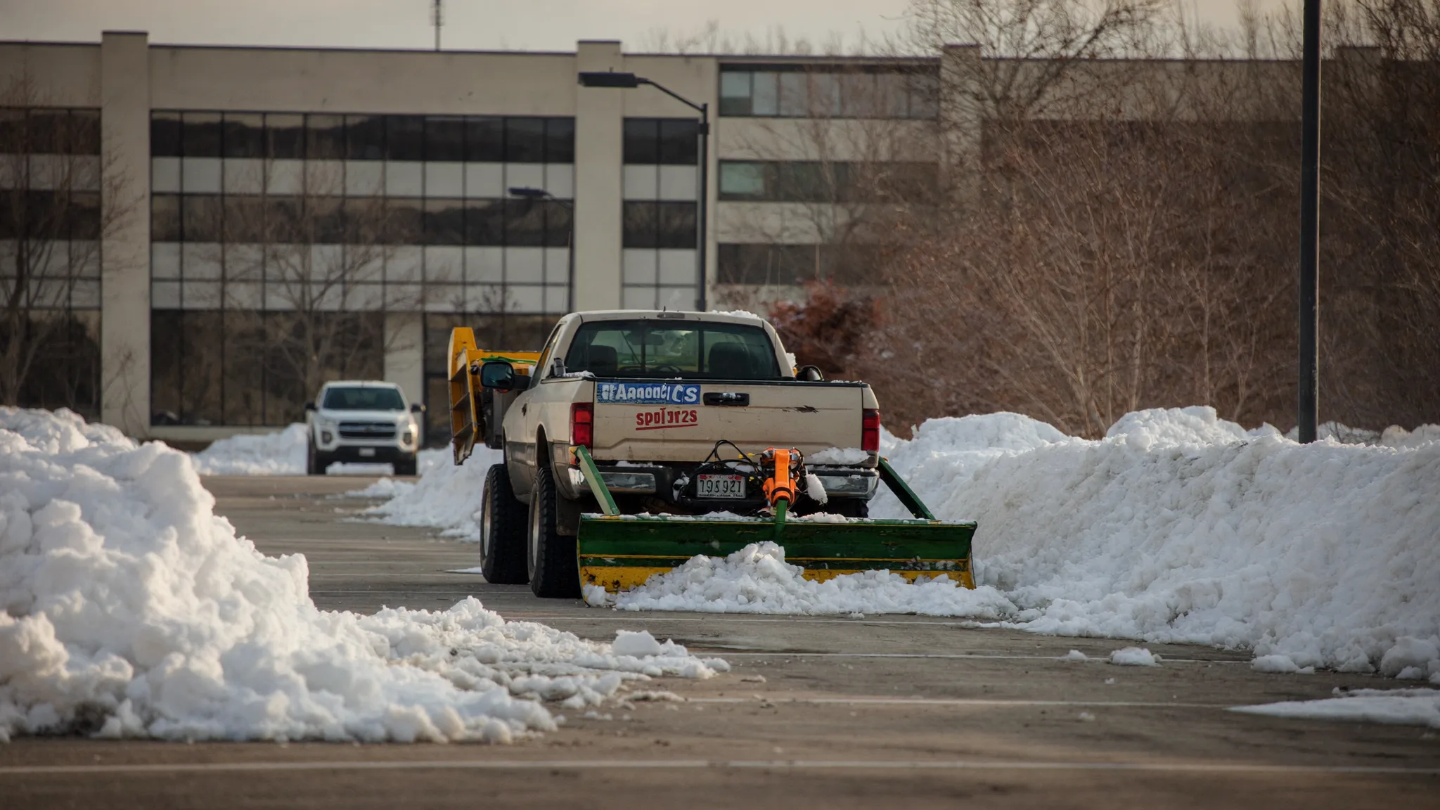 Plow truck clearing snow from a commercial parking lot