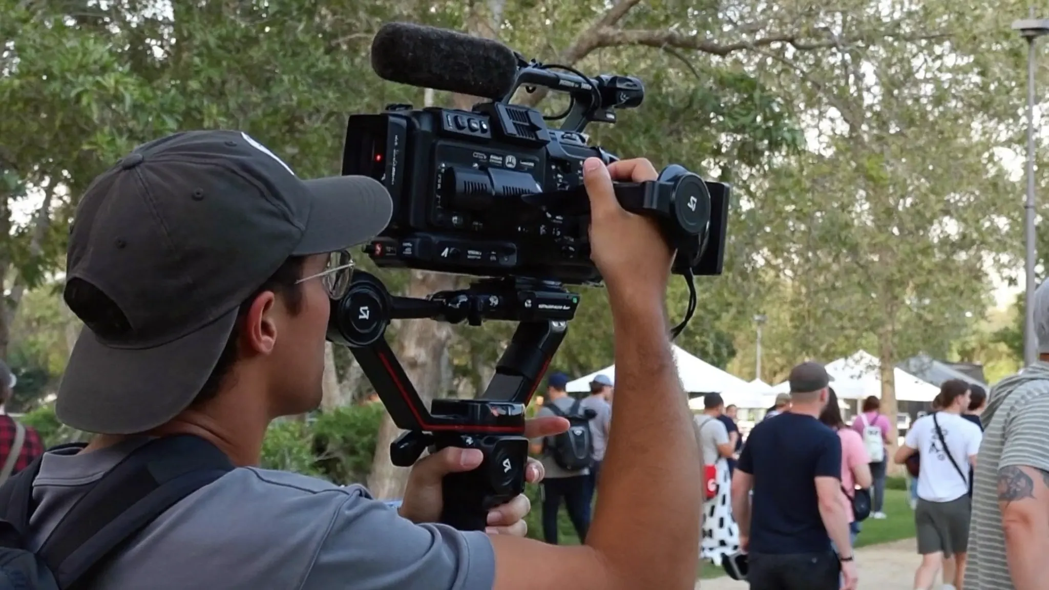 Videographer holding a camera on a gimbal stabilizer filming outdoors
